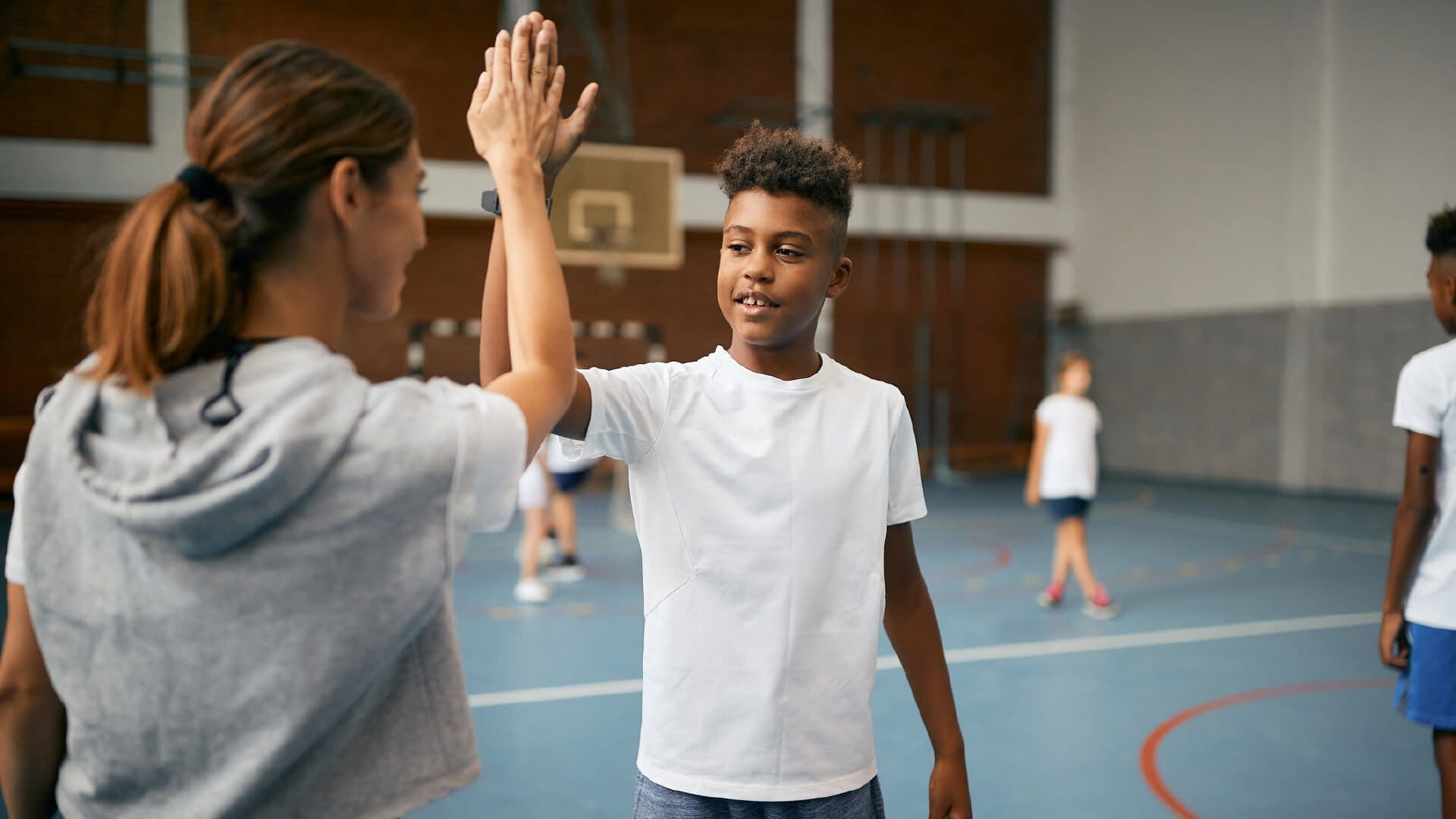 A student high fives a PE teacher.