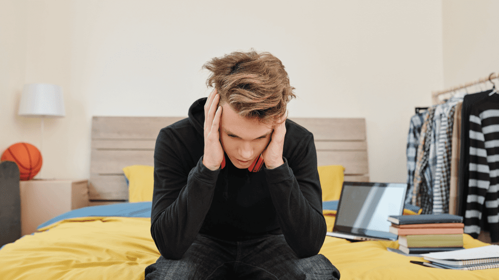 Student sits frustrated in his bedroom with homework.