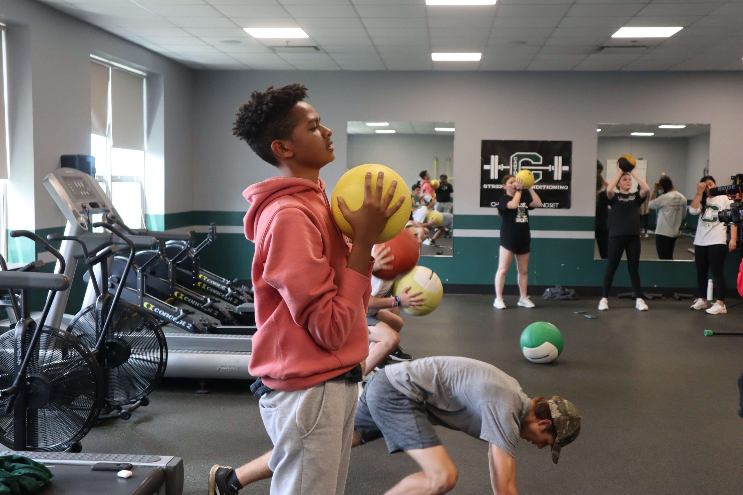 A student holds a medball during a fitness PE class.