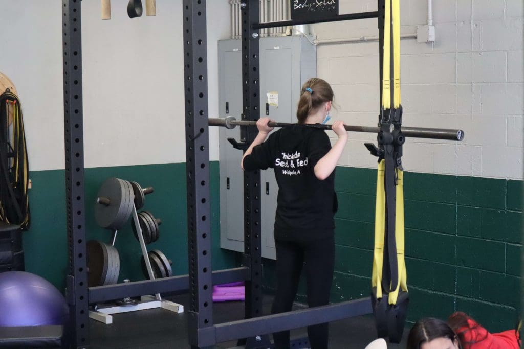 A student prepares for barbell back squat during a physical education class.