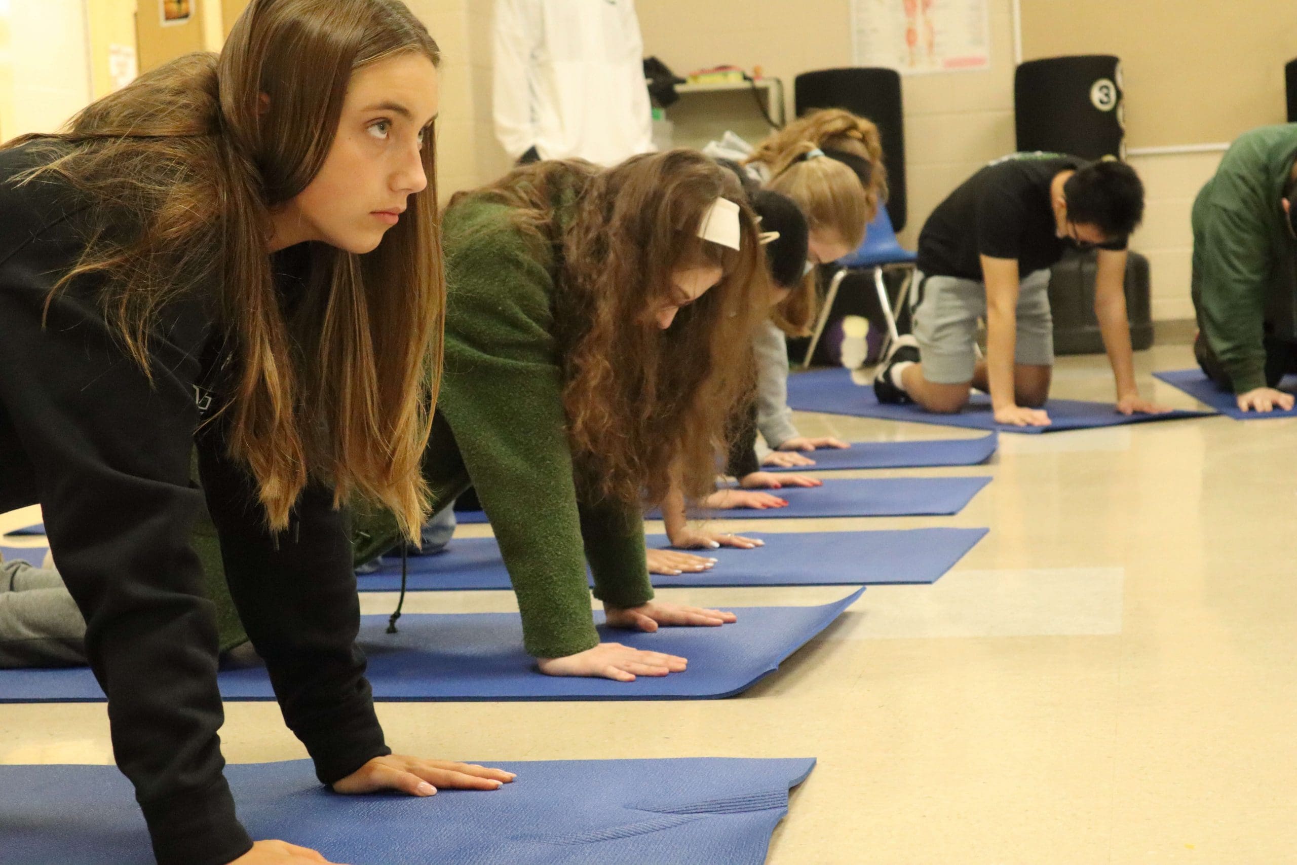 Students follow along to a PLT4M yoga lesson during physical education class.