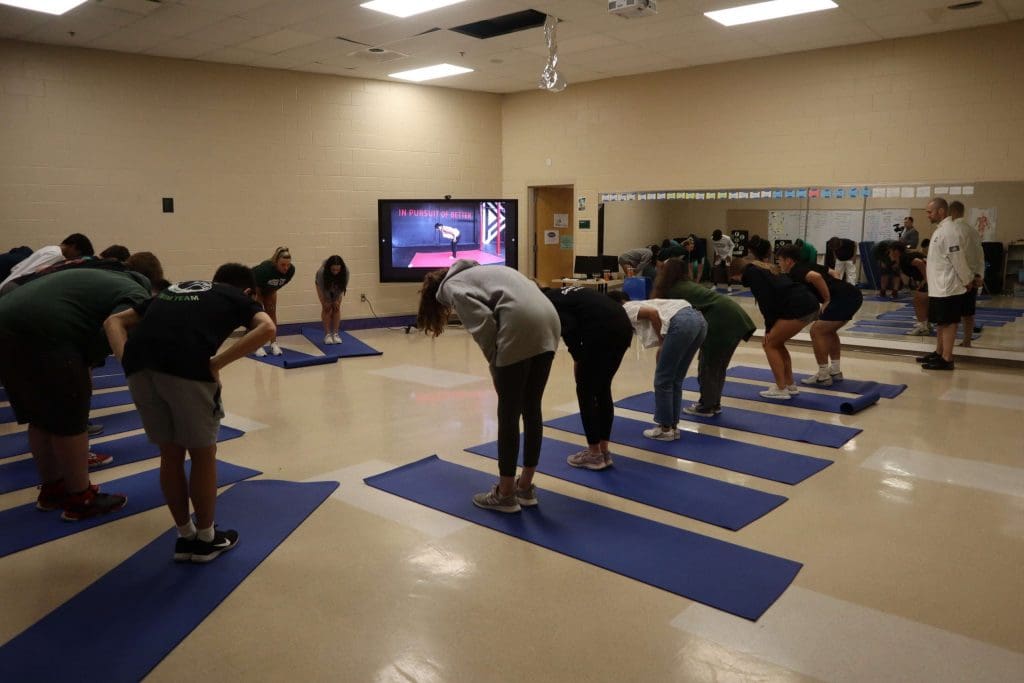 Students follow along to a PLT4M yoga lesson during physical education class.