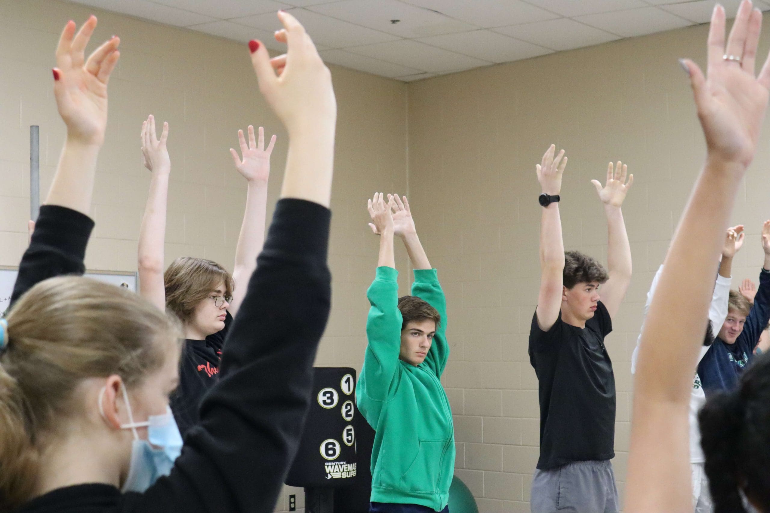 Students reach arms overhead during a yoga lesson in physical education class.