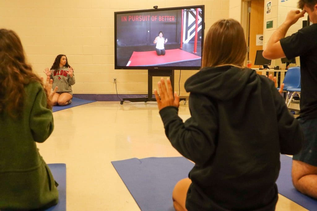 Two students practices a kneeling table top during a yoga lesson in physical education class.