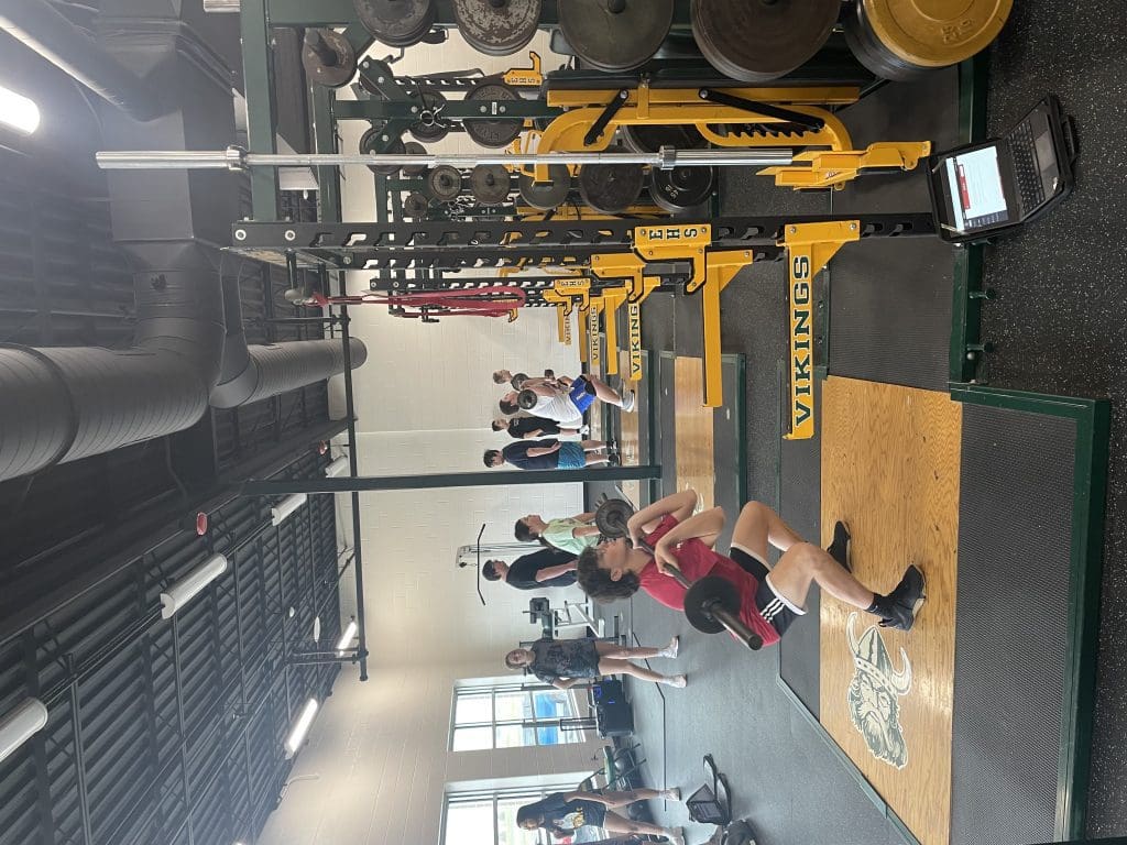 Students perform the barbell hang clean movement in a physical education class at Evergreen High School.