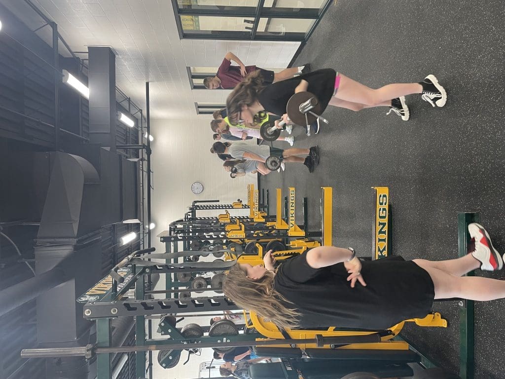 Students perform the barbell hang clean movement in a physical education class at Evergreen High School.