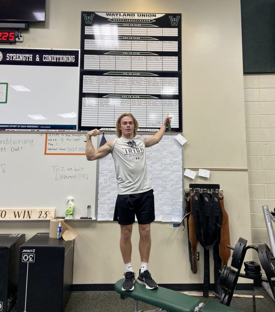 A student points at a leaderboard in a strength and conditioning class.