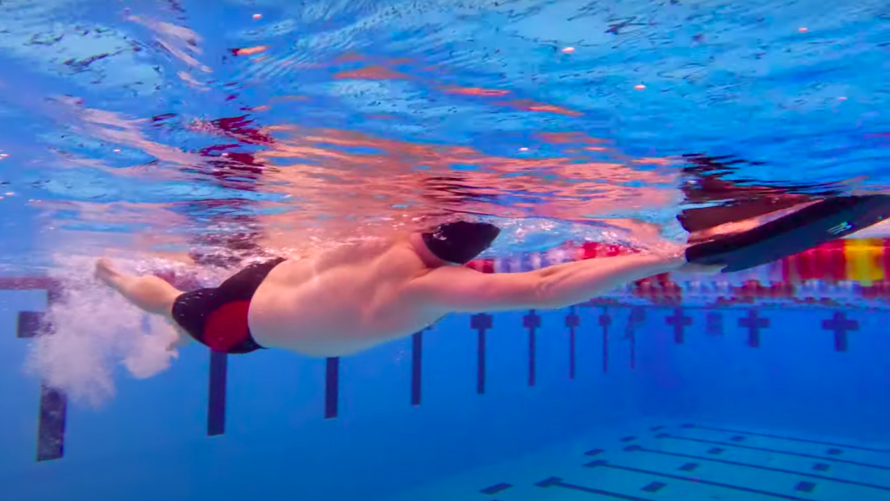 Swimmer uses a kickboard when practicing freestyle.